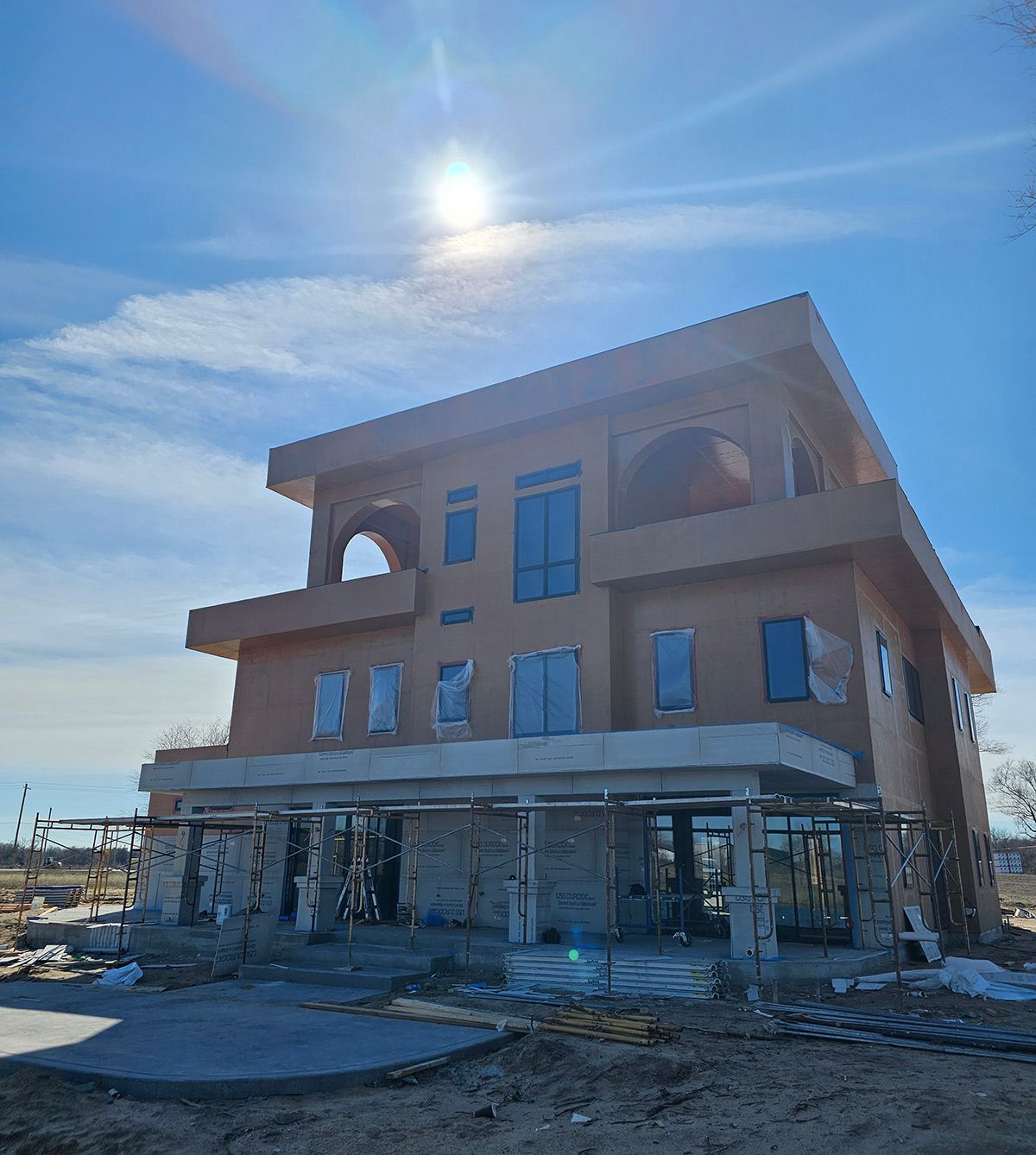 A large house under construction with the sun shining through above it