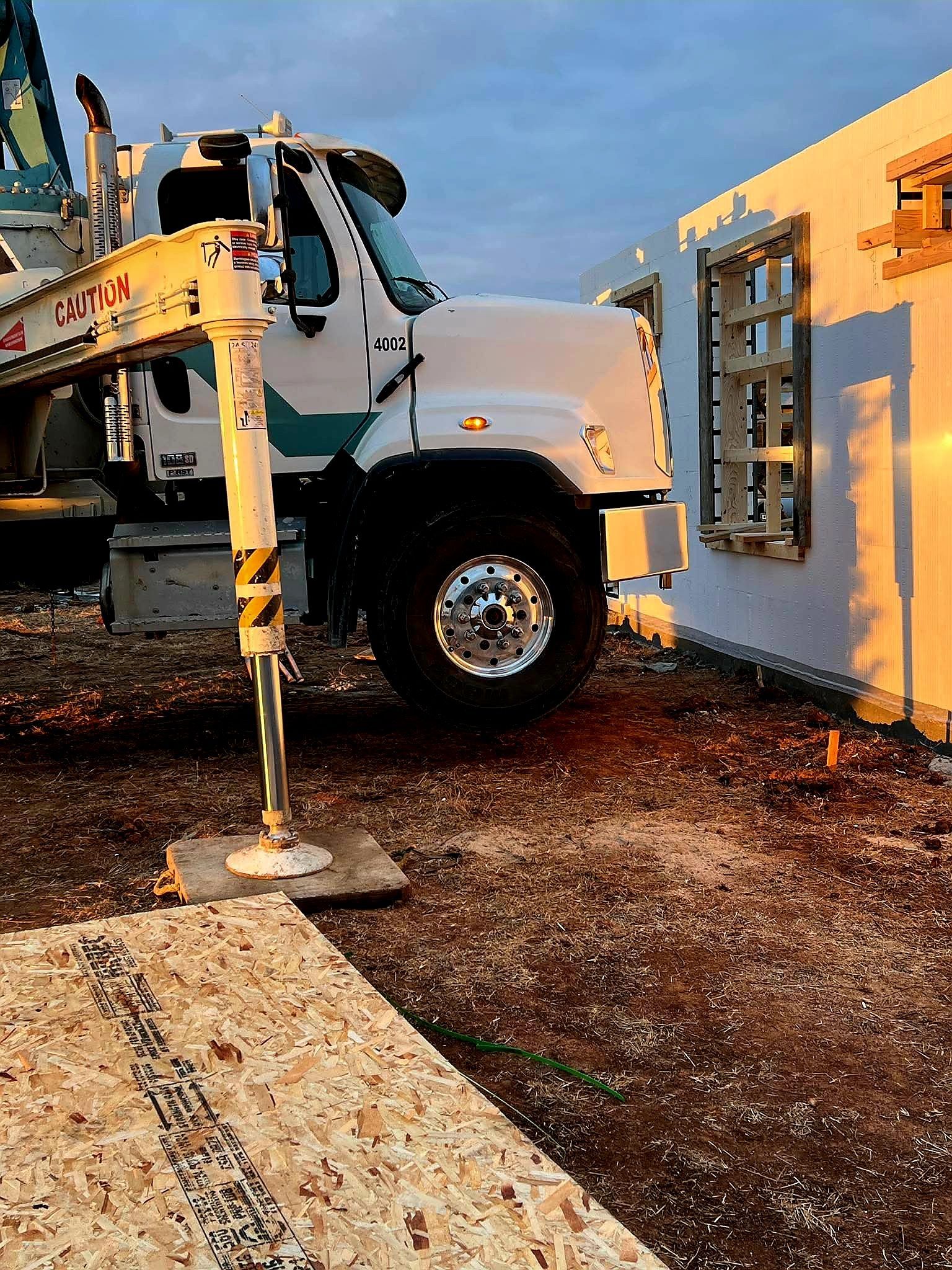 Construction site with a white cement truck lifting a wall panel.
