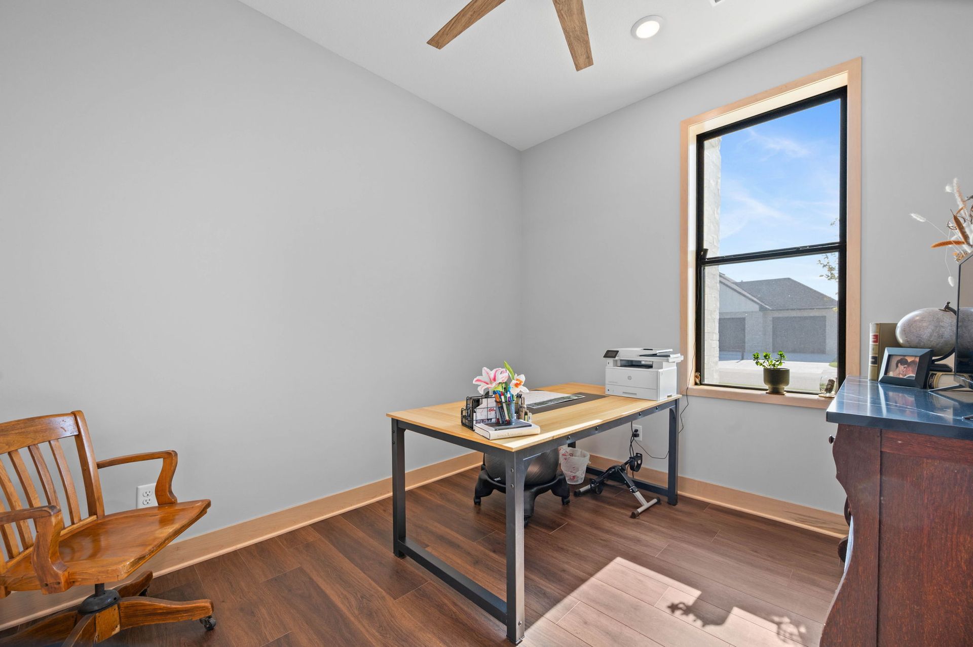 A room with a desk, chair, dresser, and window.