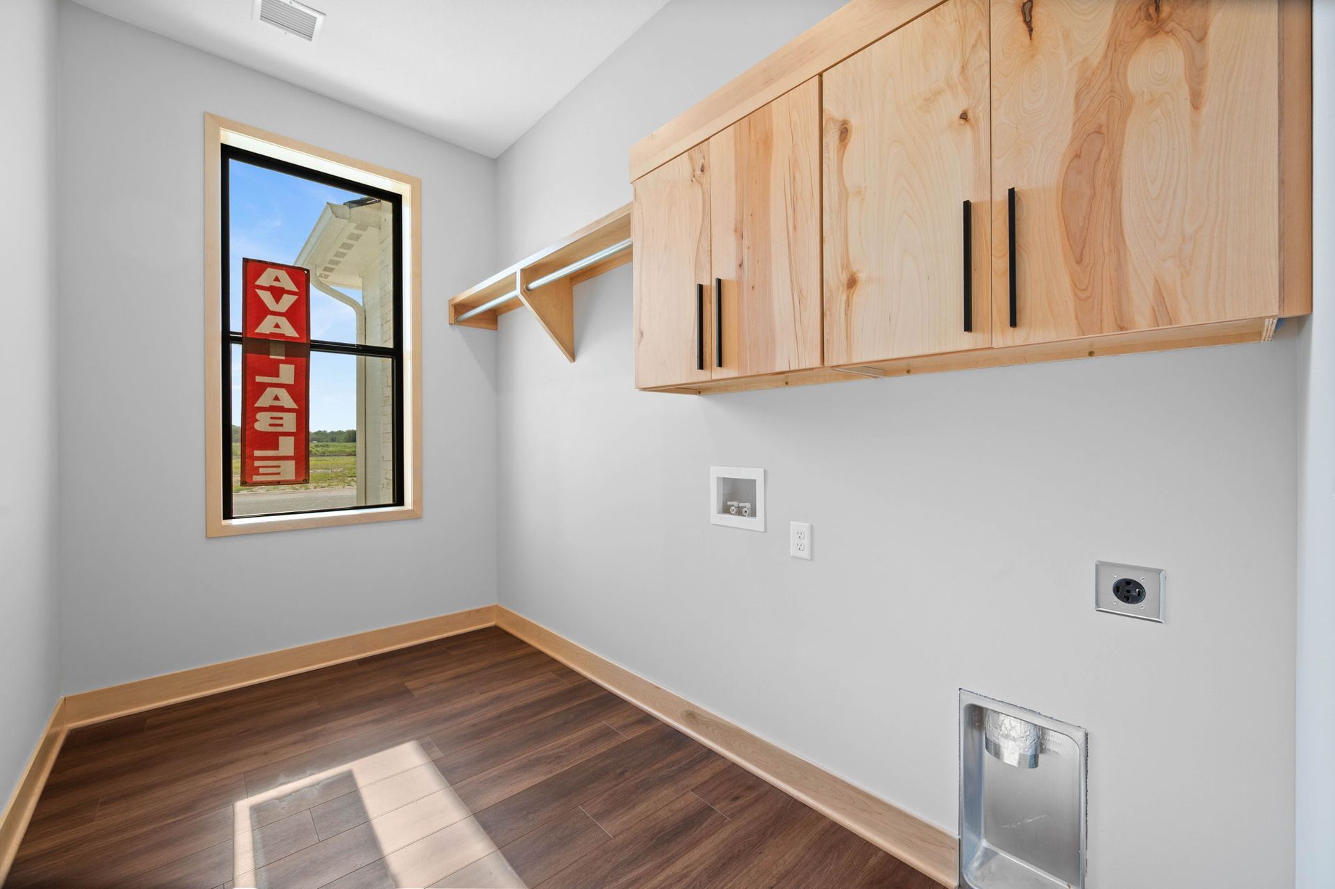 A laundry room with wooden cabinets and a window.