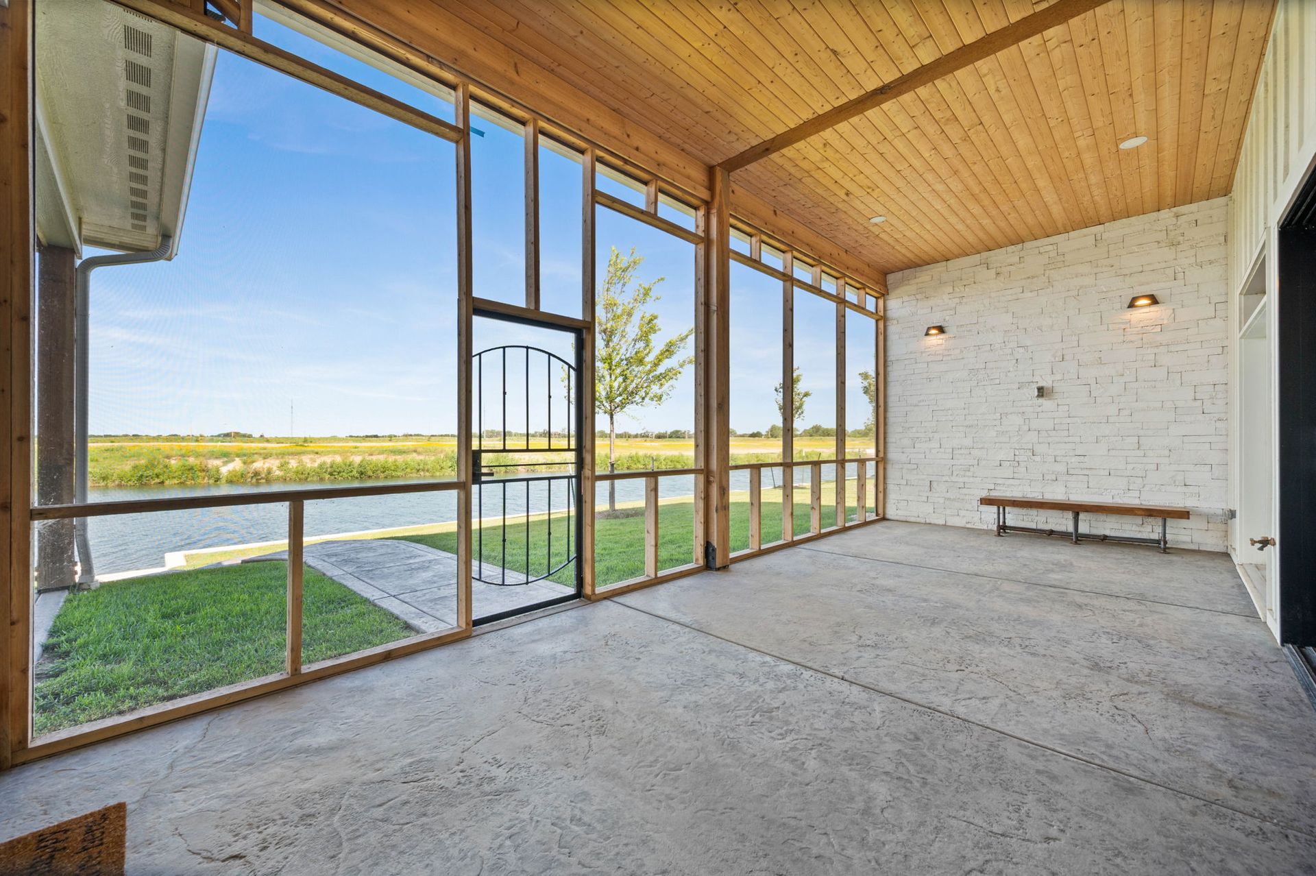 A screened in porch with a lot of windows and a bench.