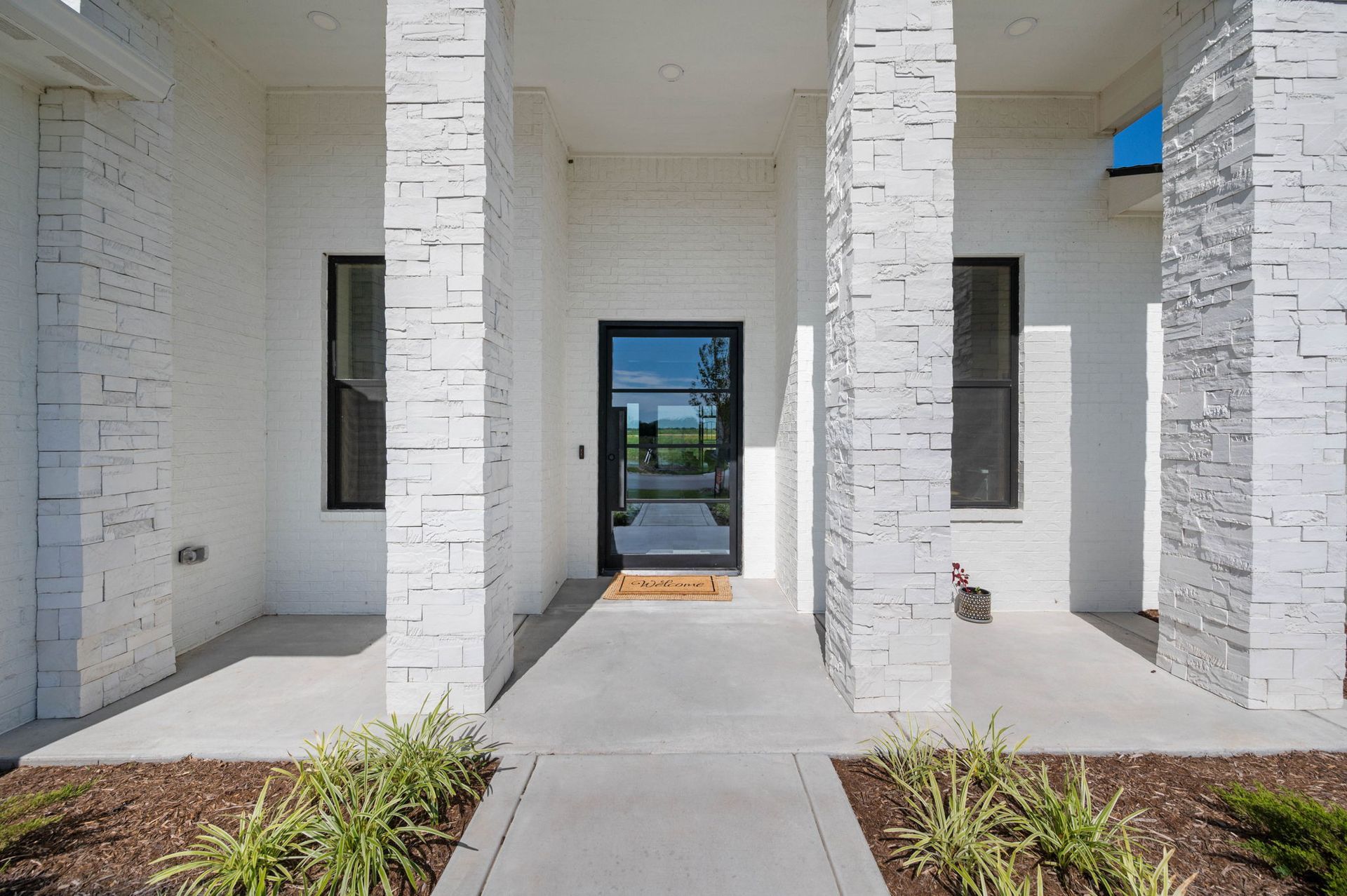 The front of a white house with columns and a glass door.