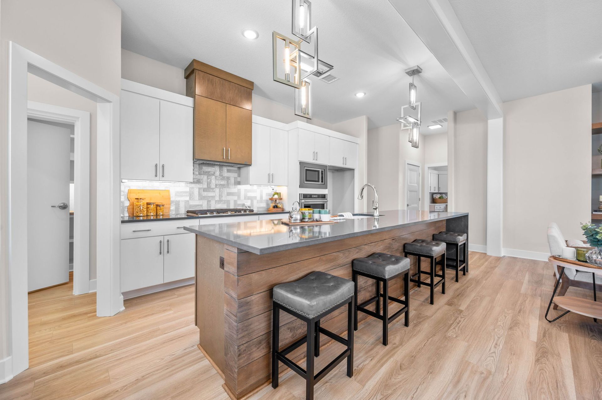 A kitchen with white cabinets and a large island with stools.