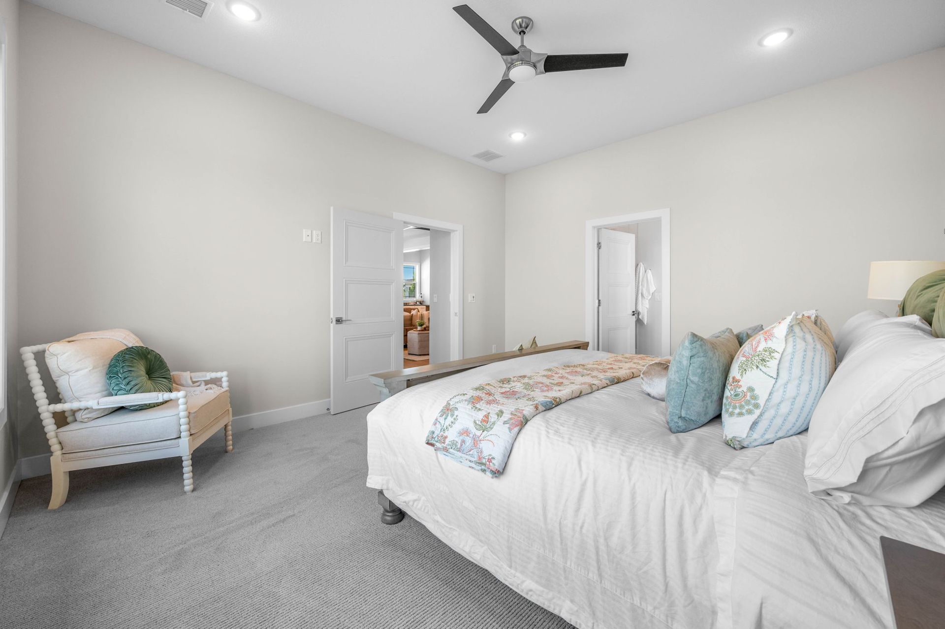 A bedroom with a bed, chair, and ceiling fan.