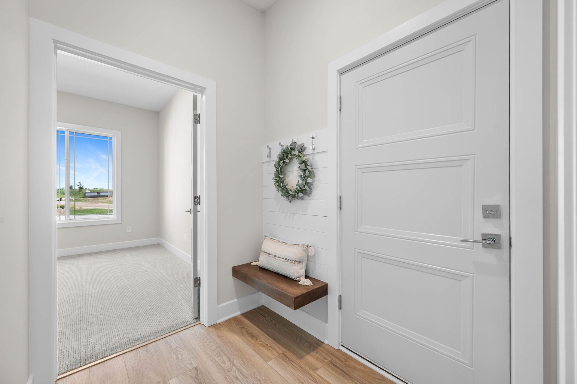 A hallway with a shelf and a wreath on the wall.