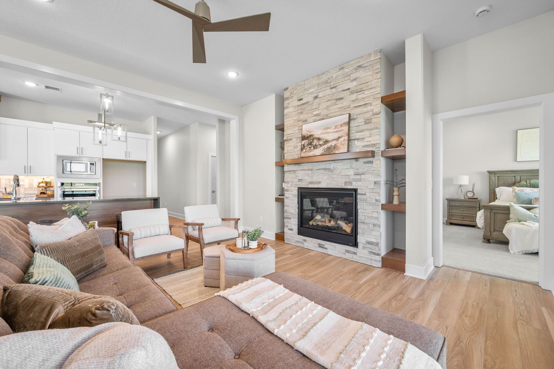A living room with a couch, chairs, a fireplace, and a ceiling fan.