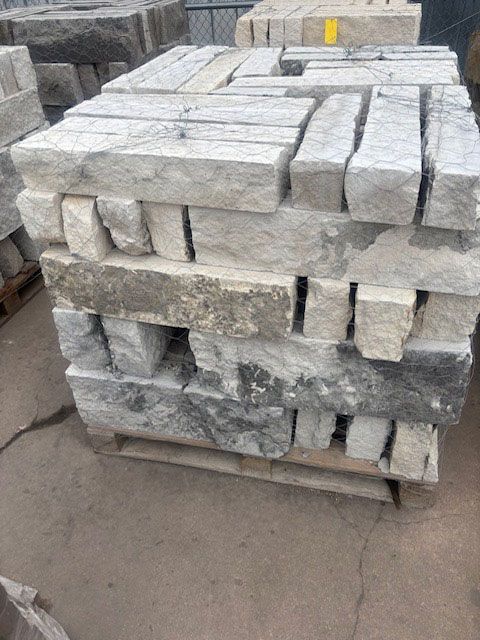 Stack of light gray stone blocks on a wooden pallet, outdoors.