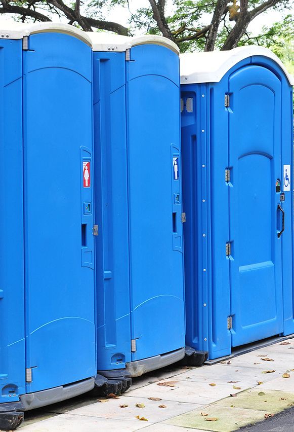 three blue portable toilets are lined up on a sidewalk 