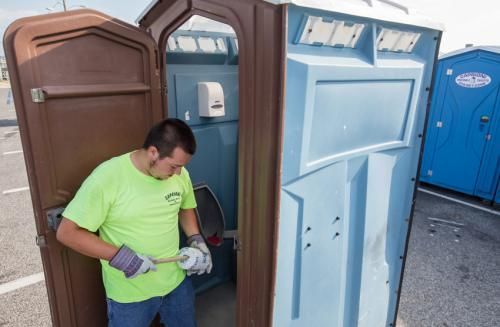 a man is cleaning a portable toilet with a brush 