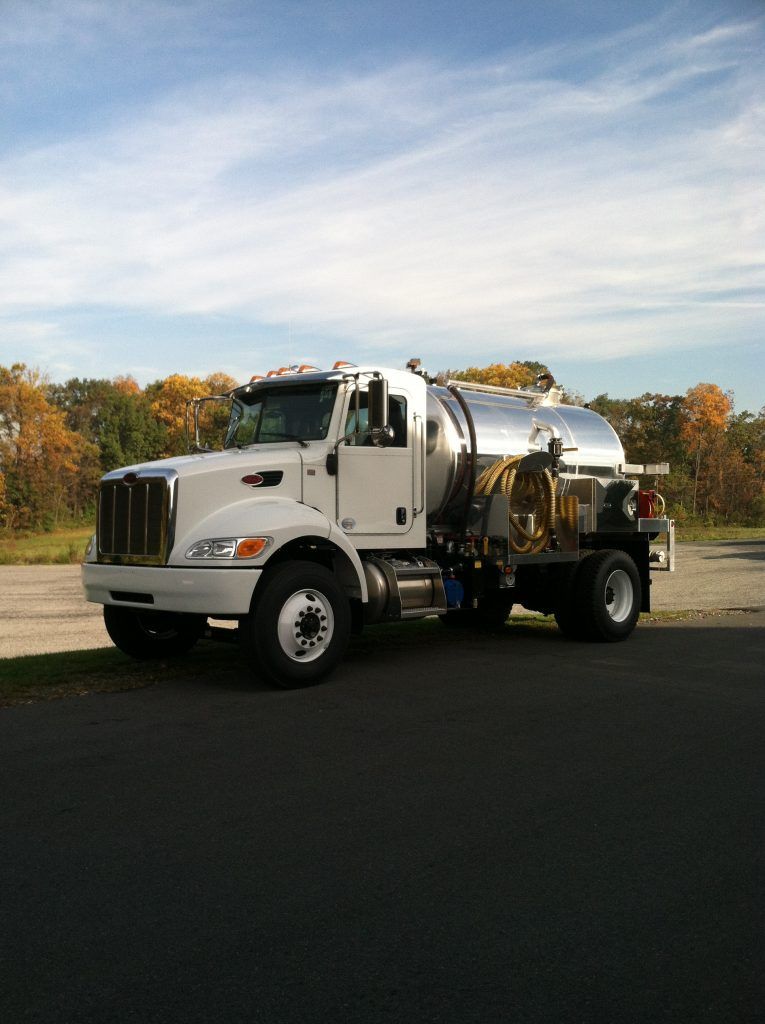 a white tanker truck is parked on the side of the road 
