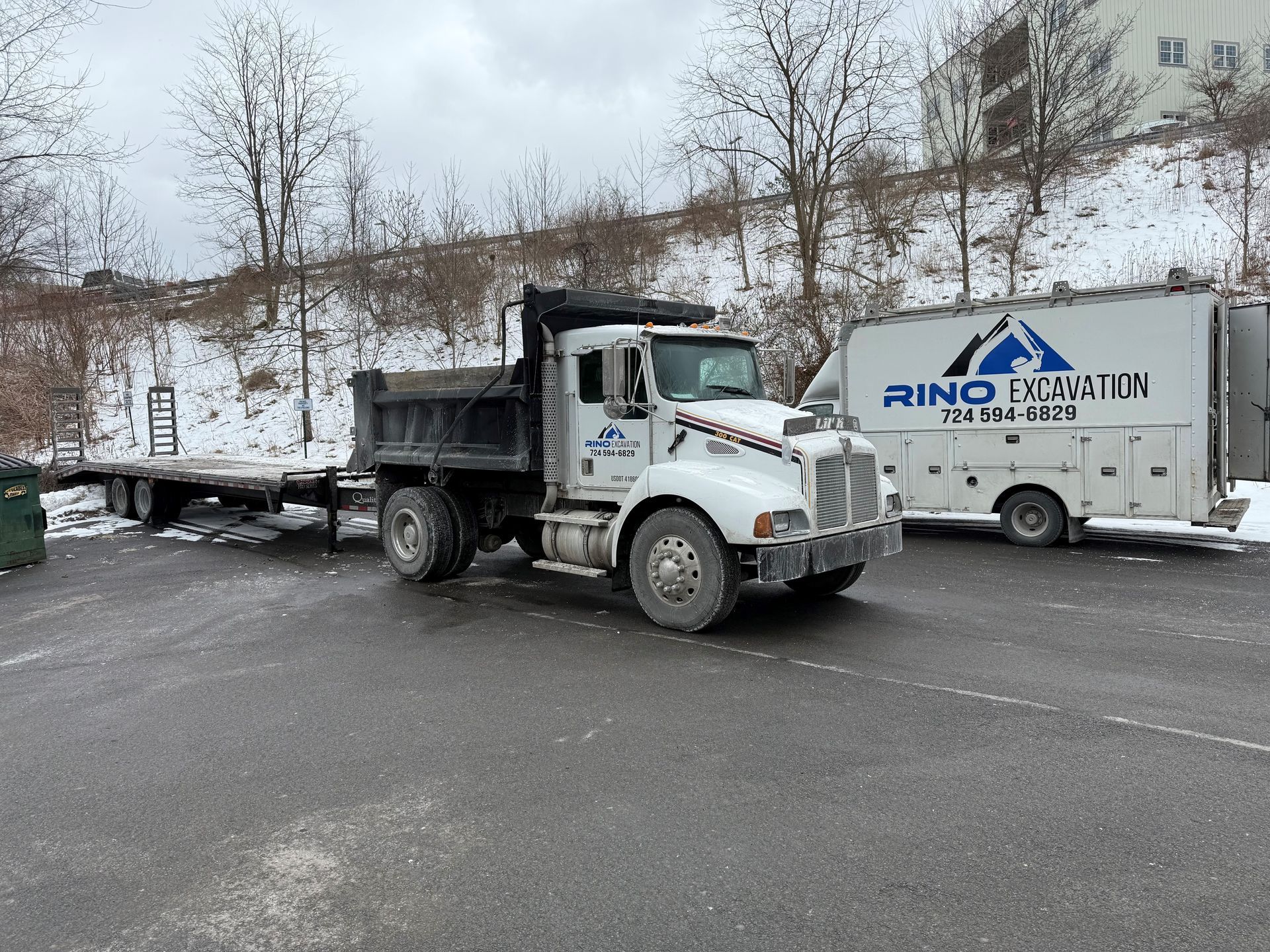 A dump truck is parked in a parking lot next to a white van.
