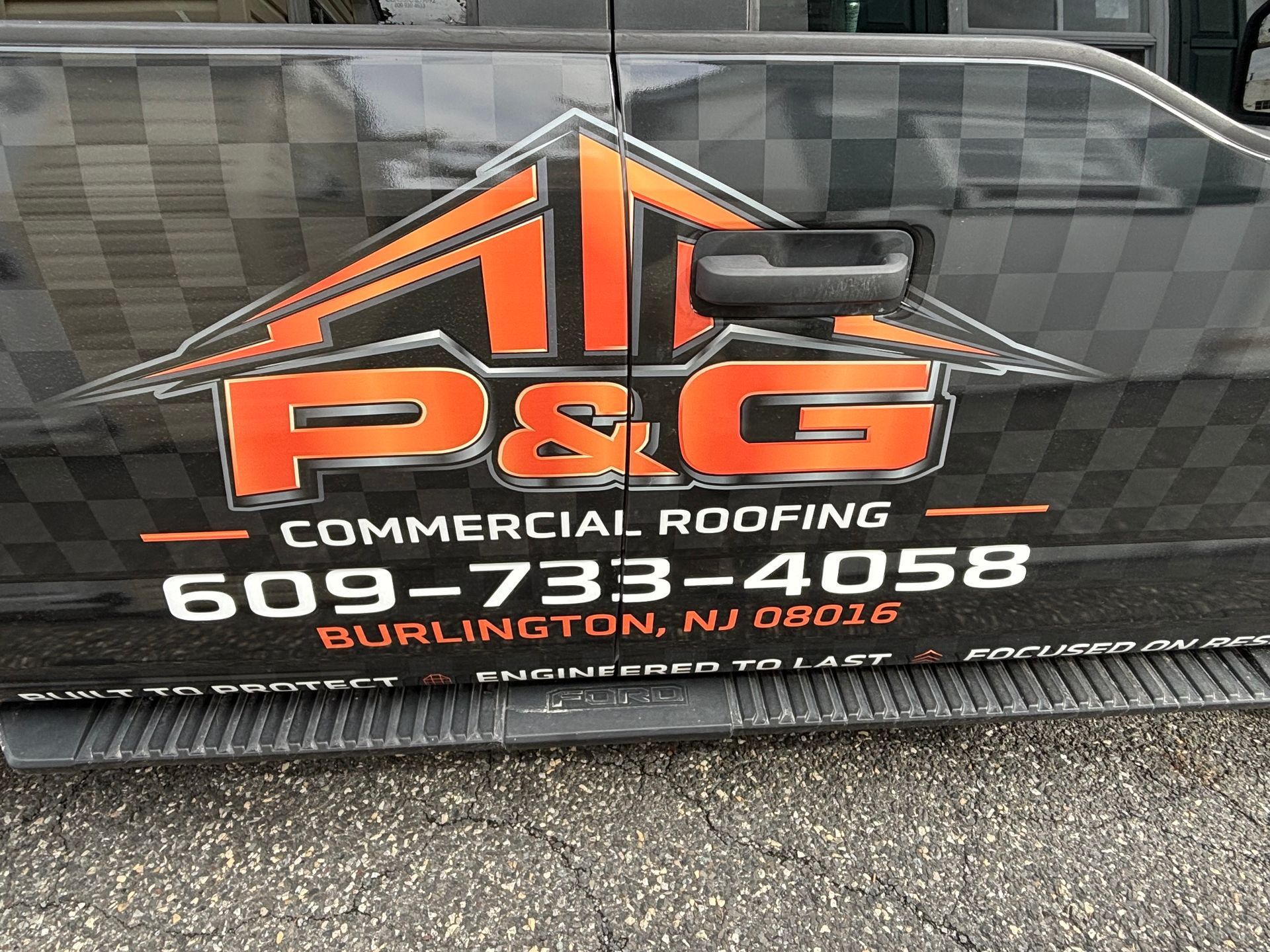 Orange and black P&G Commercial Roofing truck door decal with phone number and website info