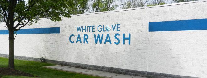 A white wall with the words white glove car wash painted on it