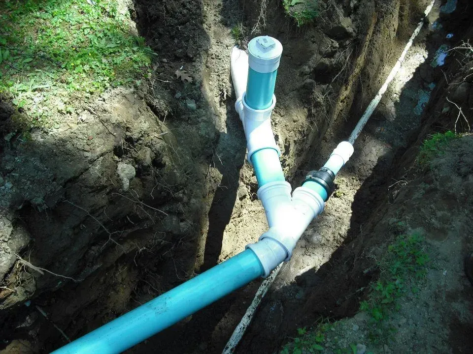 Blue PVC pipes in a trench, connected in a Y-shape underground