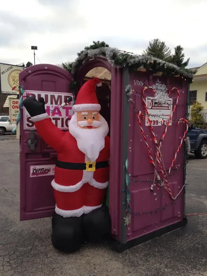 Santa statue beside a pink phone booth decorated with greenery and candy canes