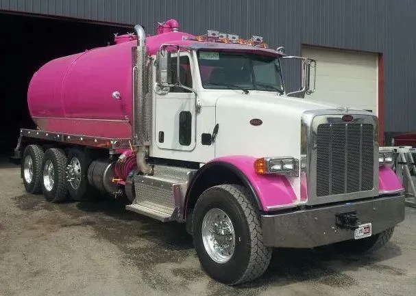 Pink tanker truck parked outside a garage