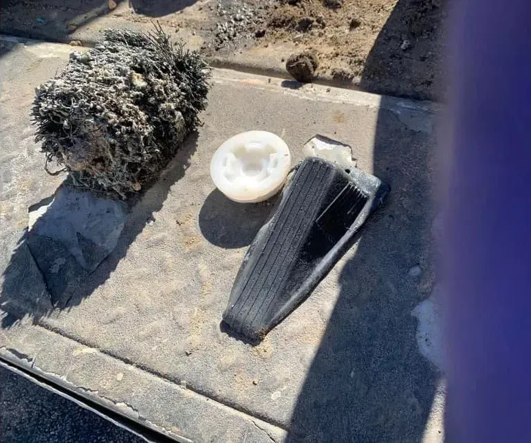Three debris items on pavement: a tangled black mass, a white bowl, and a black mesh filter.
