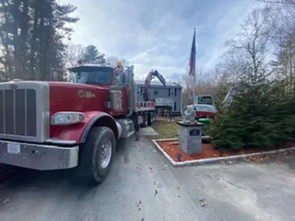 Red fire truck parked in a driveway beside a house with an American flag and shrubs