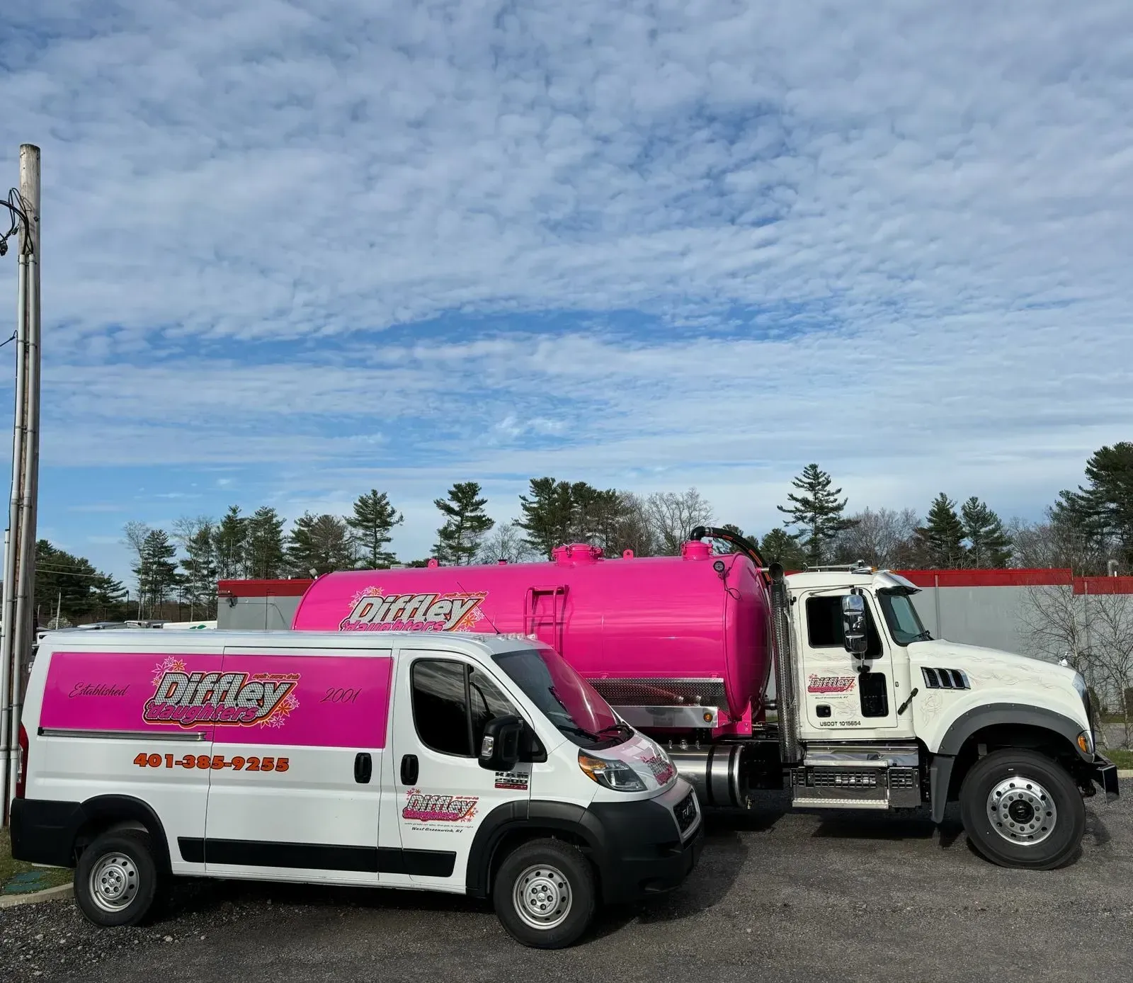 Two service vans, white and pink, parked side by side under a cloudy sky.