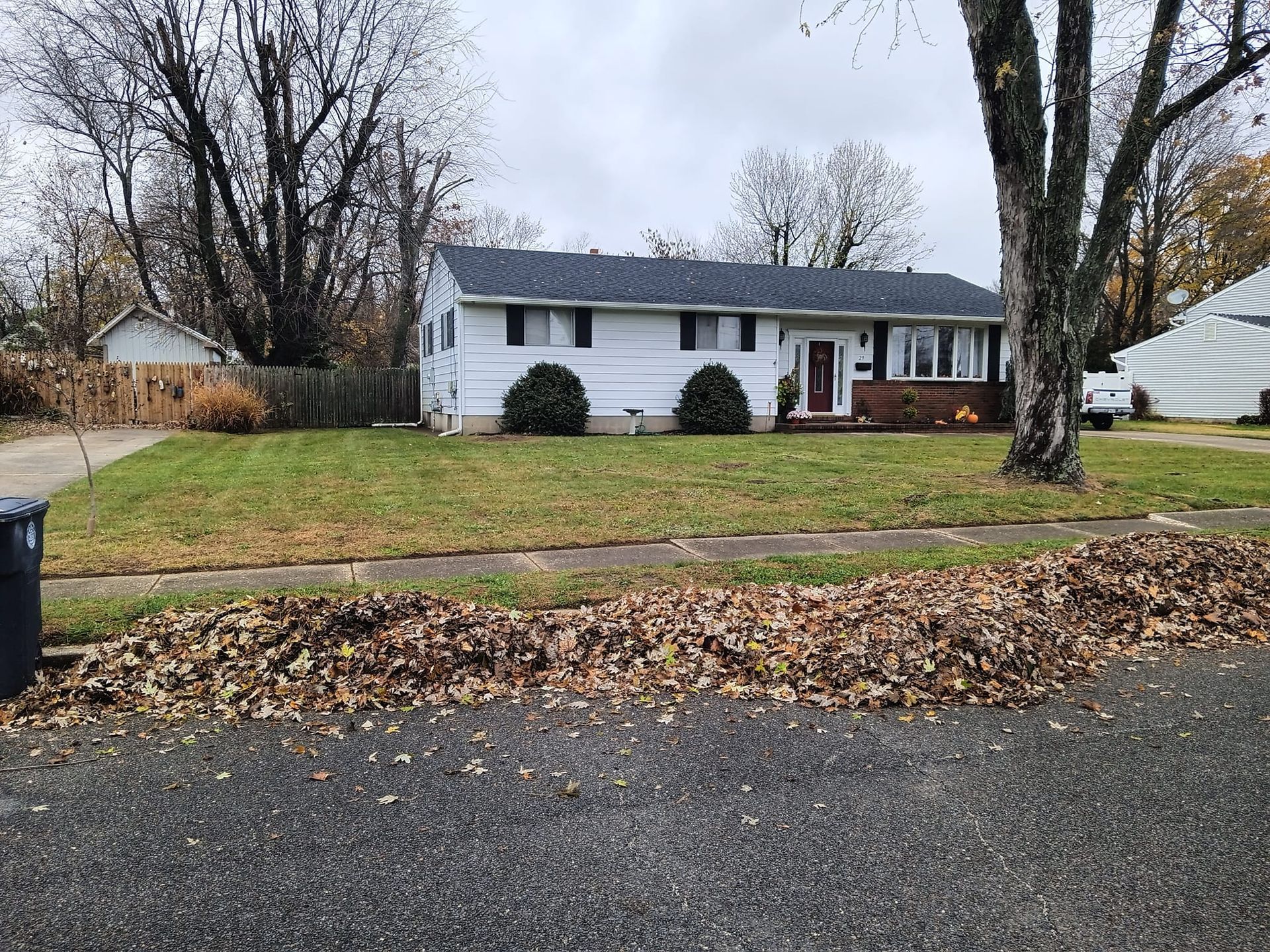 A white house with a black roof is sitting on top of a lush green lawn.