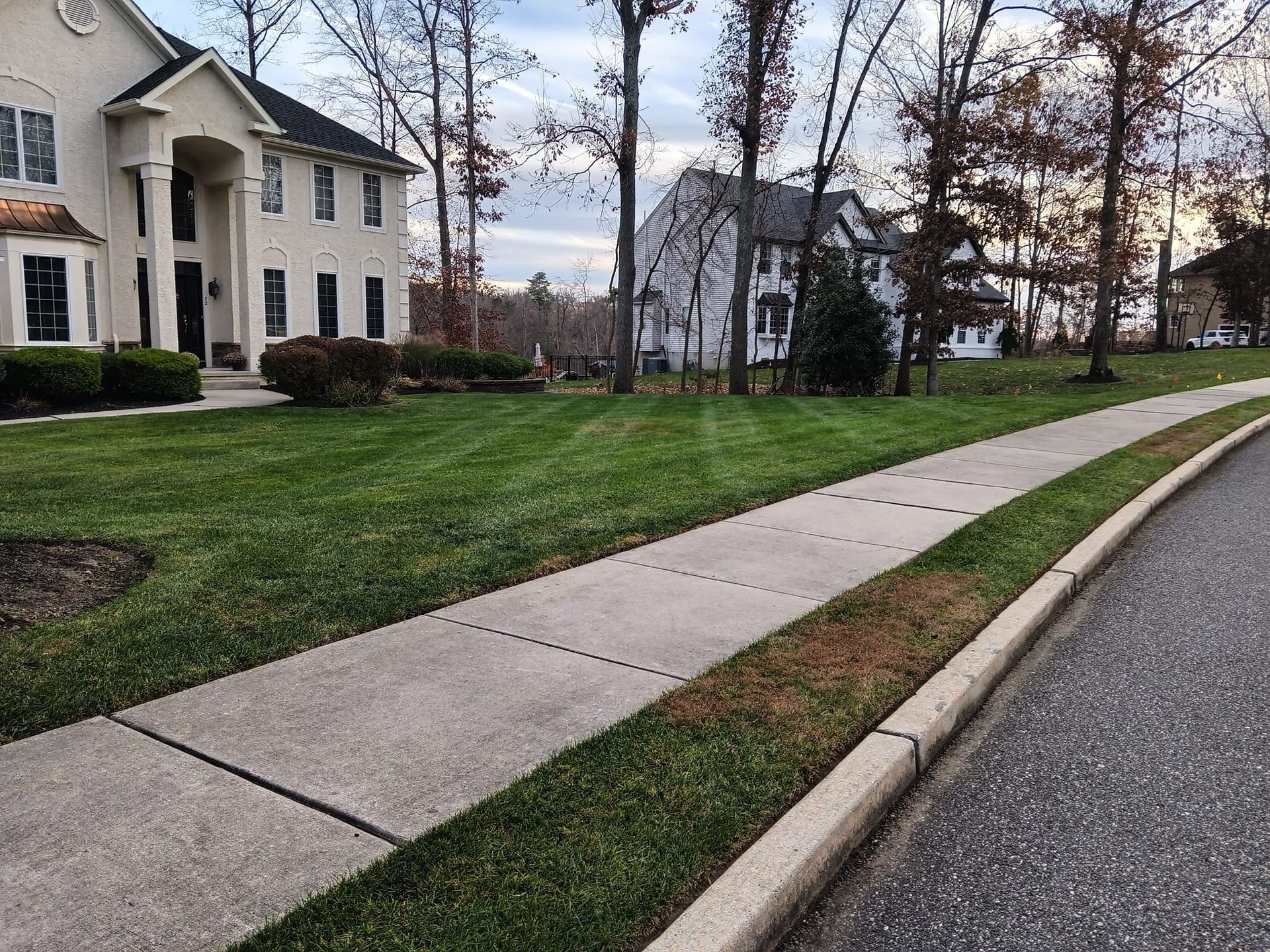 A sidewalk leading to a house with a lush green lawn