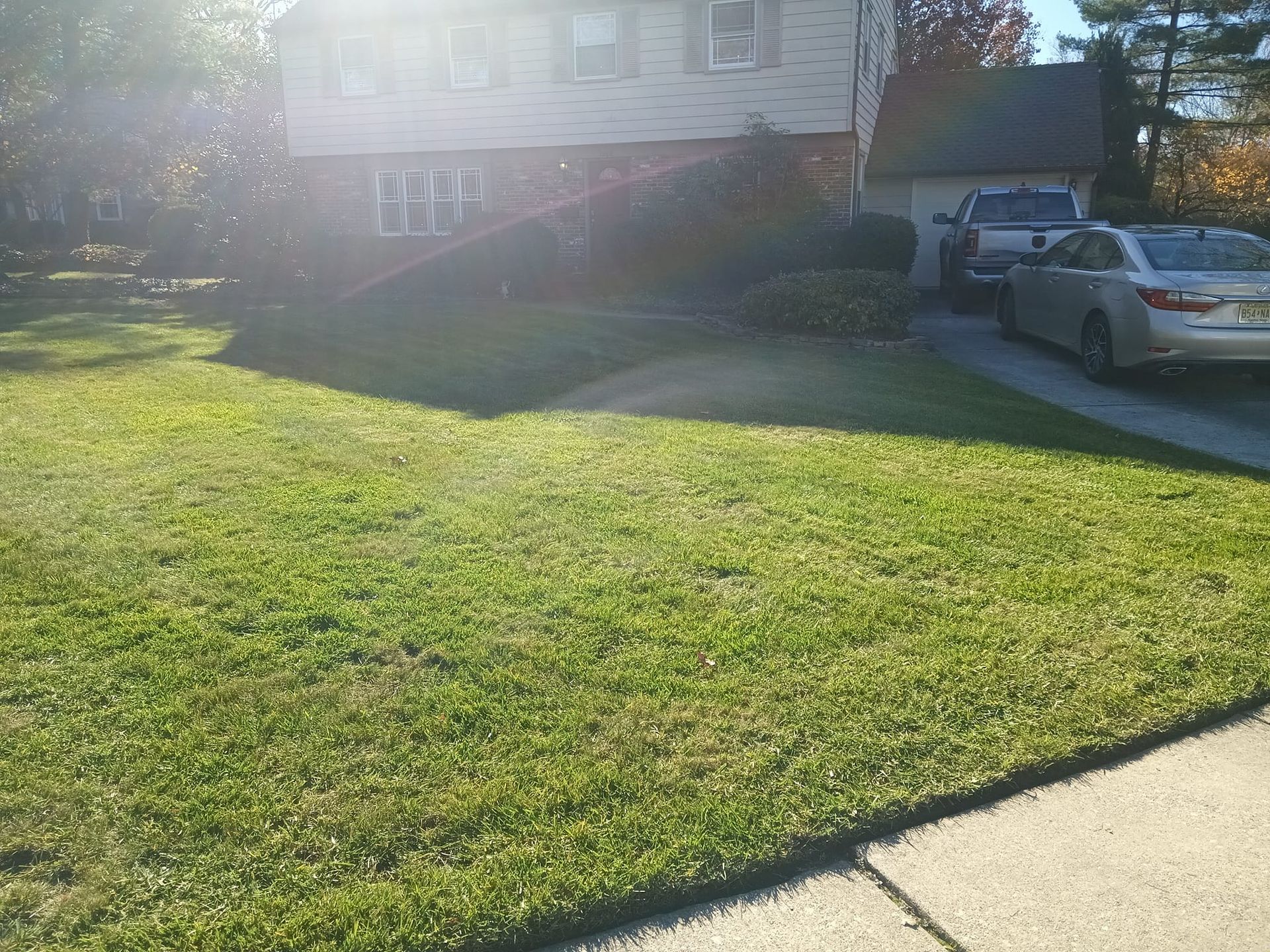 A car is parked in front of a house with a lush green lawn.