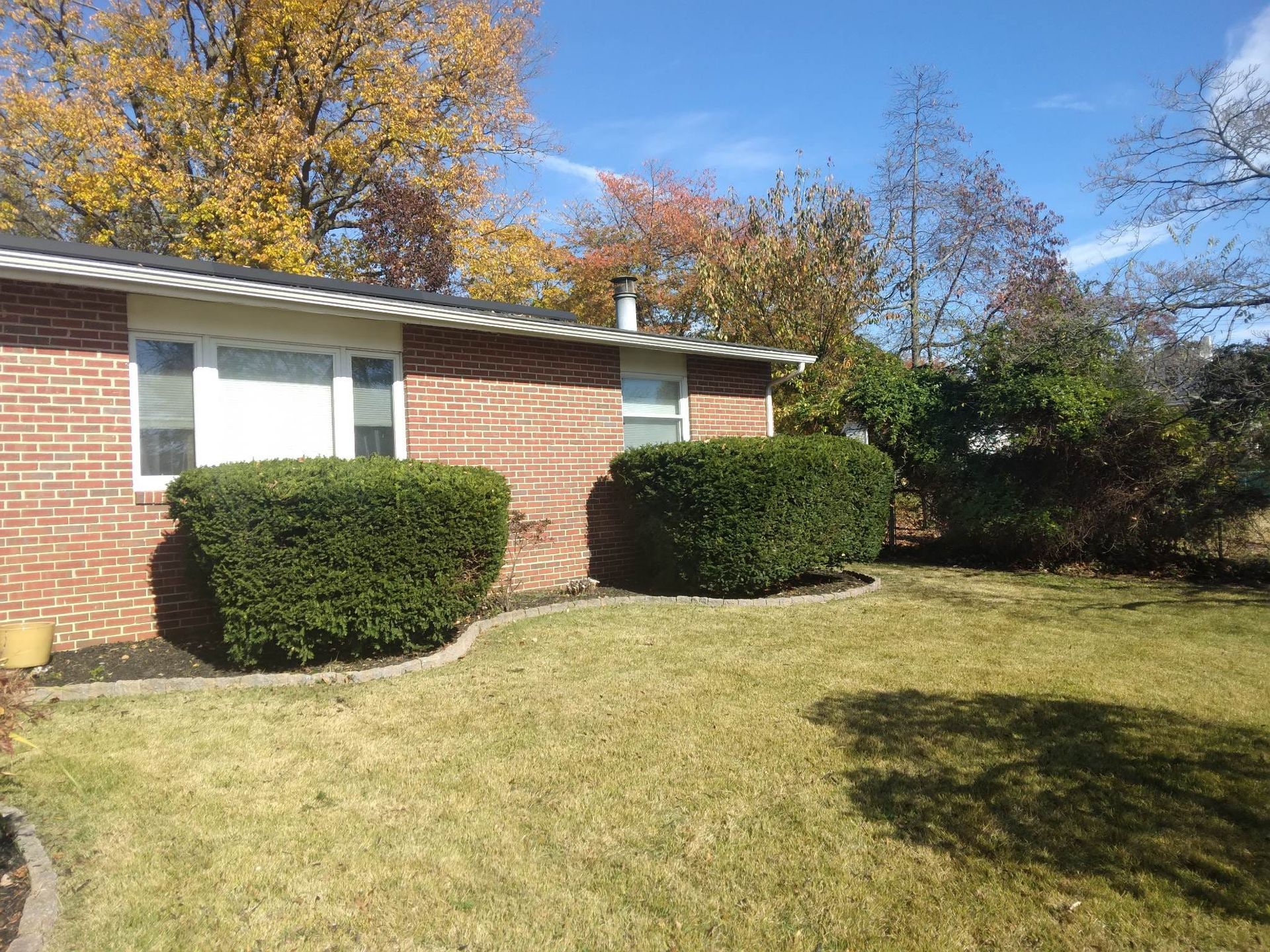 A brick house with a large lawn in front of it.