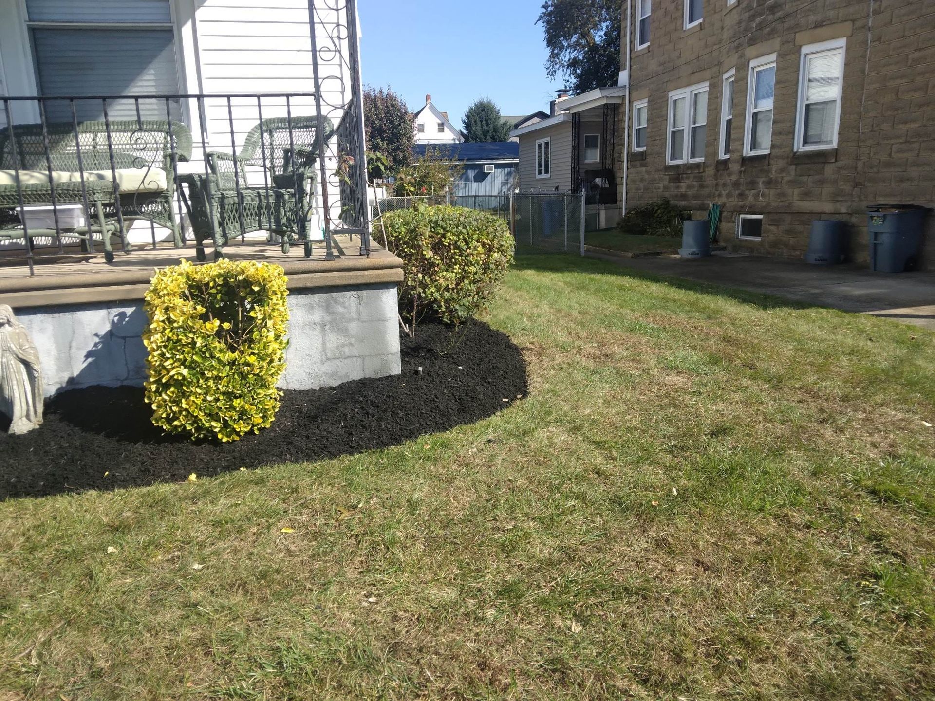 A lawn in front of a house with a brick building in the background