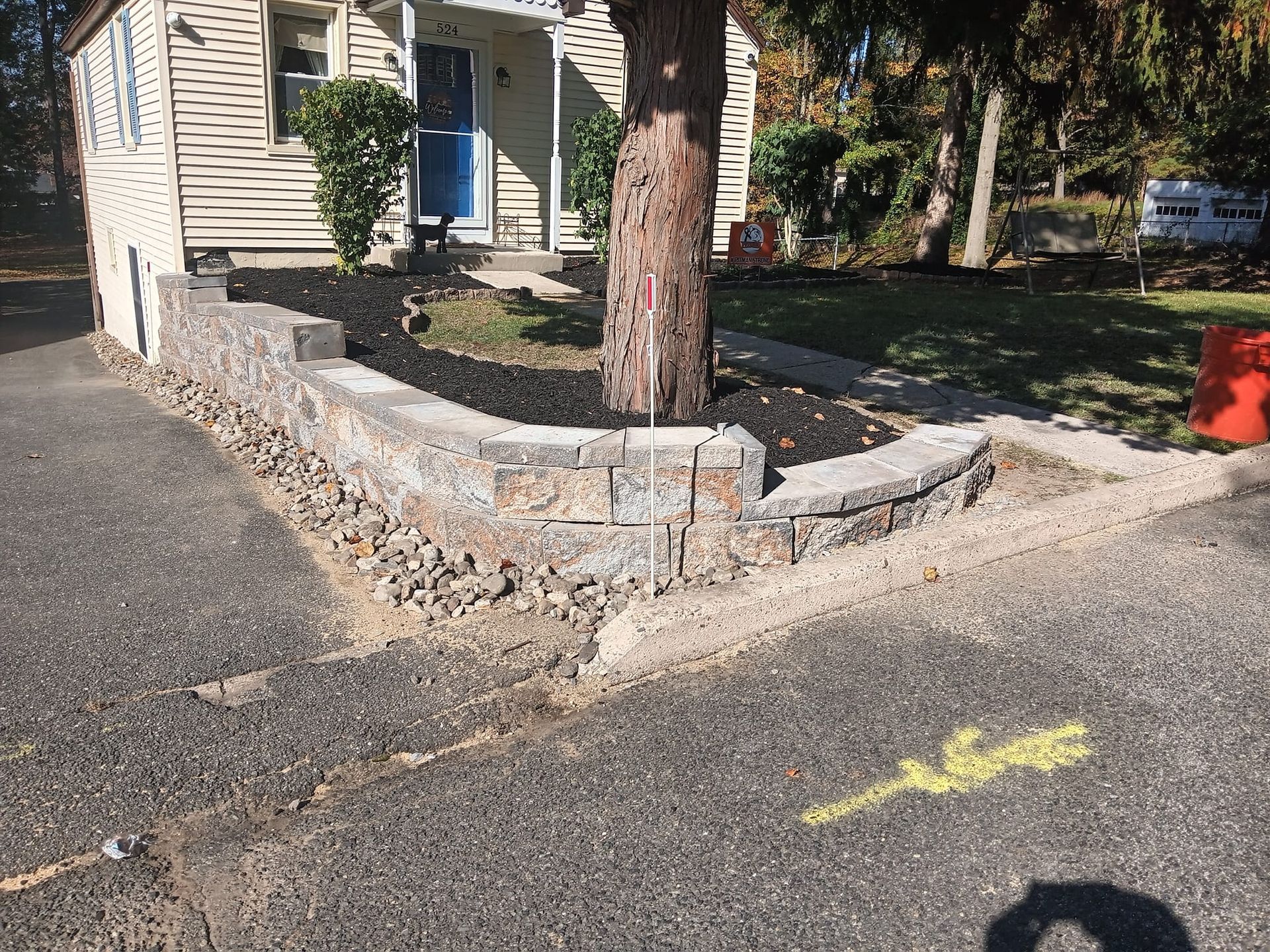 A stone wall is being built in front of a house.