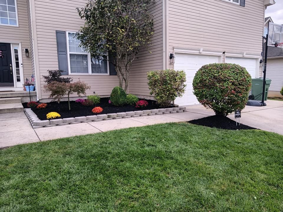 A house with a lush green lawn and a garden in front of it.
