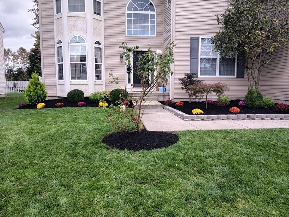 A house with a lush green lawn and flowers in front of it.