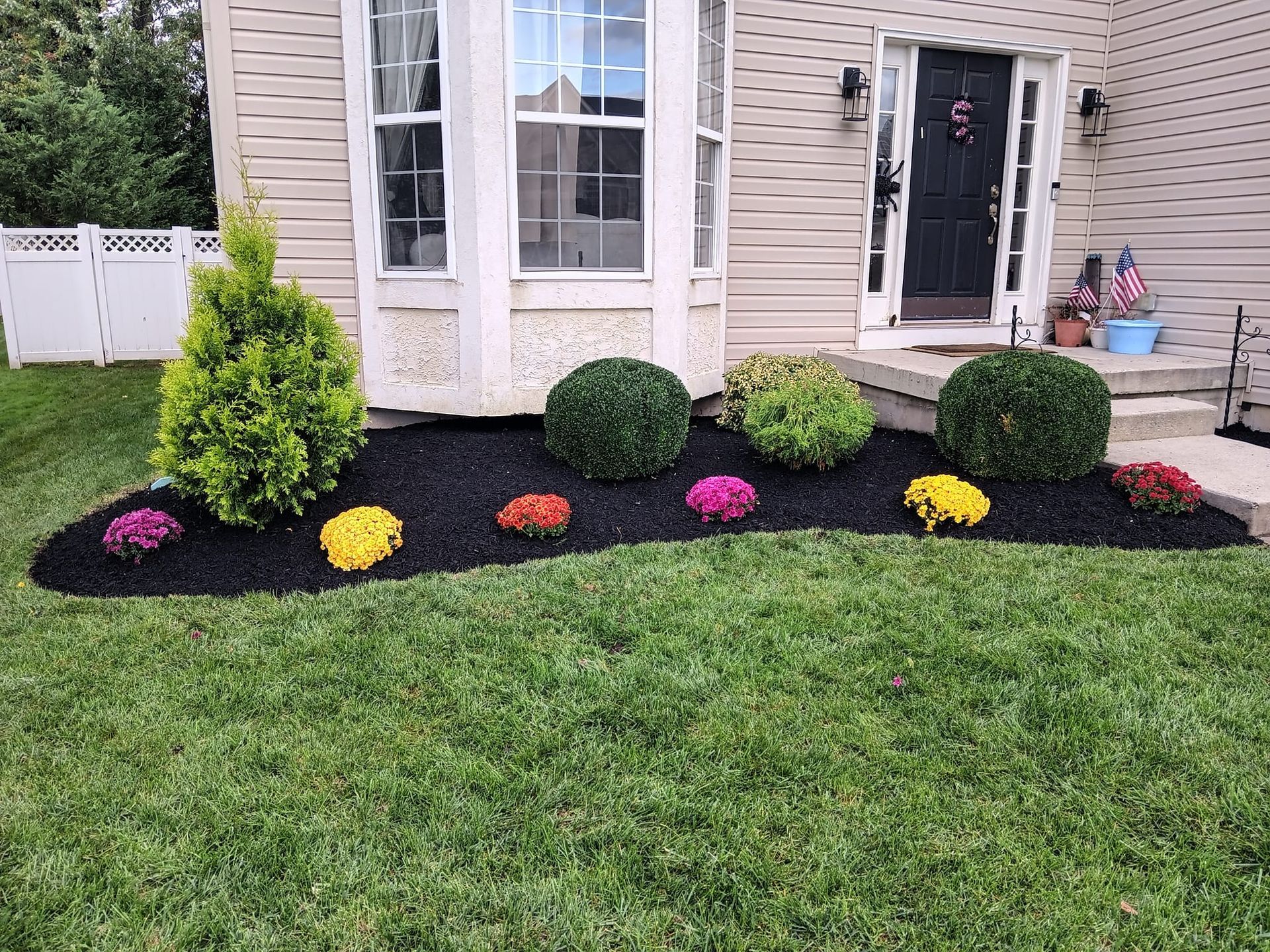 A lawn with flowers and bushes in front of a house.