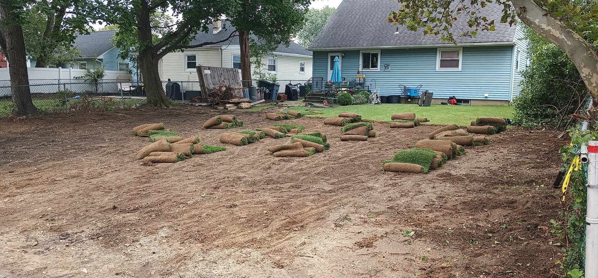 A yard with a lot of dirt and trees in front of a house.