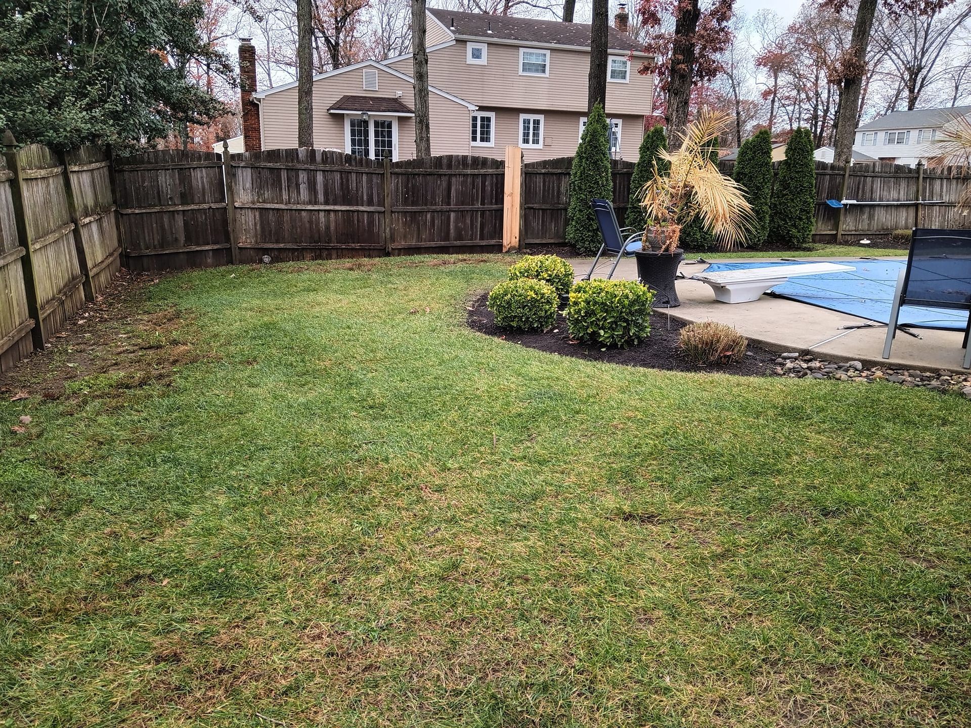 A backyard with a fence and a swimming pool.