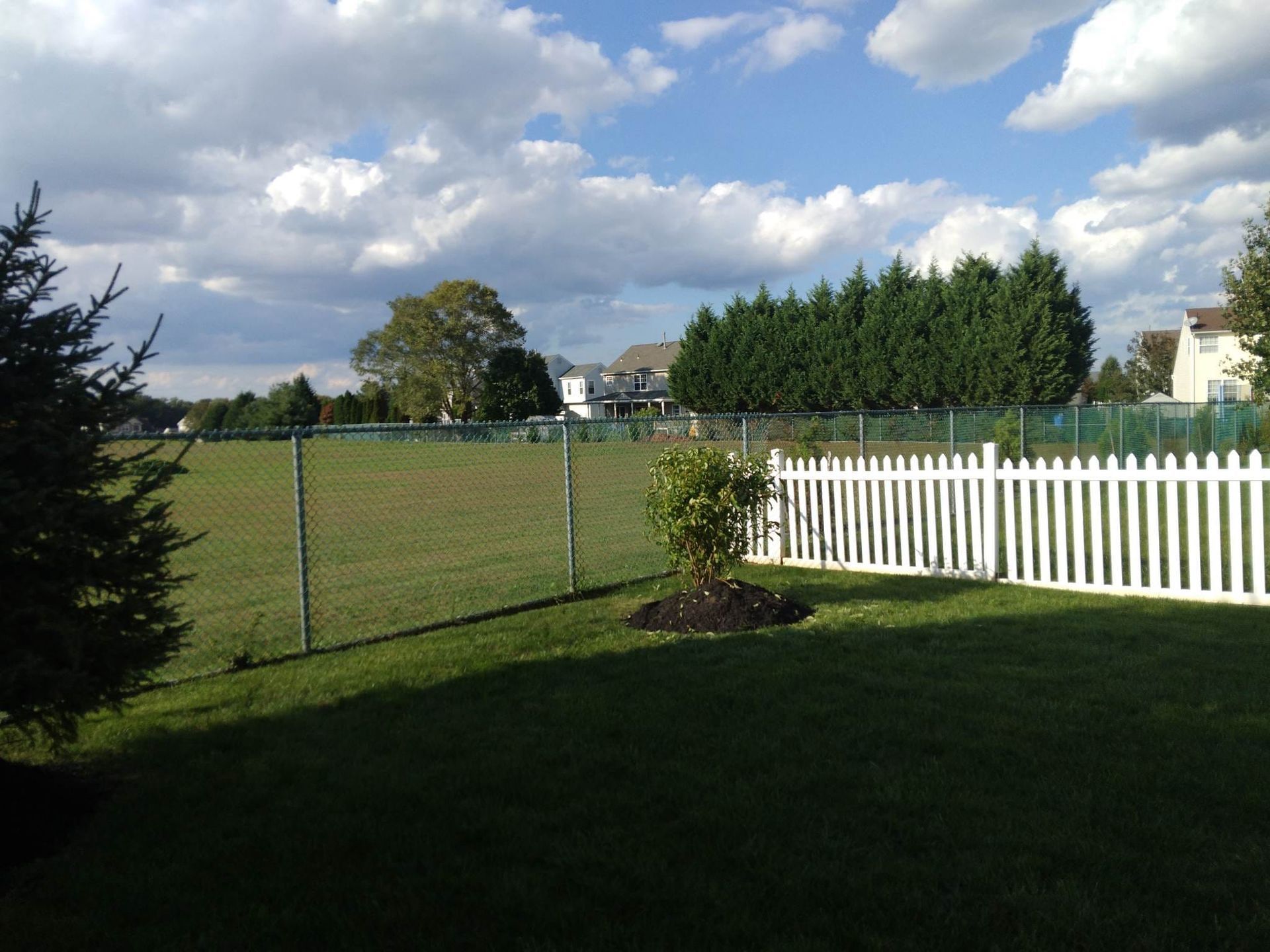 A white picket fence surrounds a lush green field