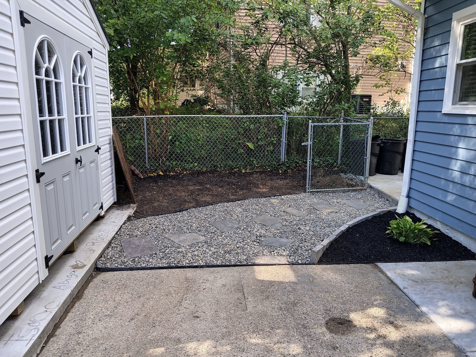 A backyard with a shed and a chain link fence.