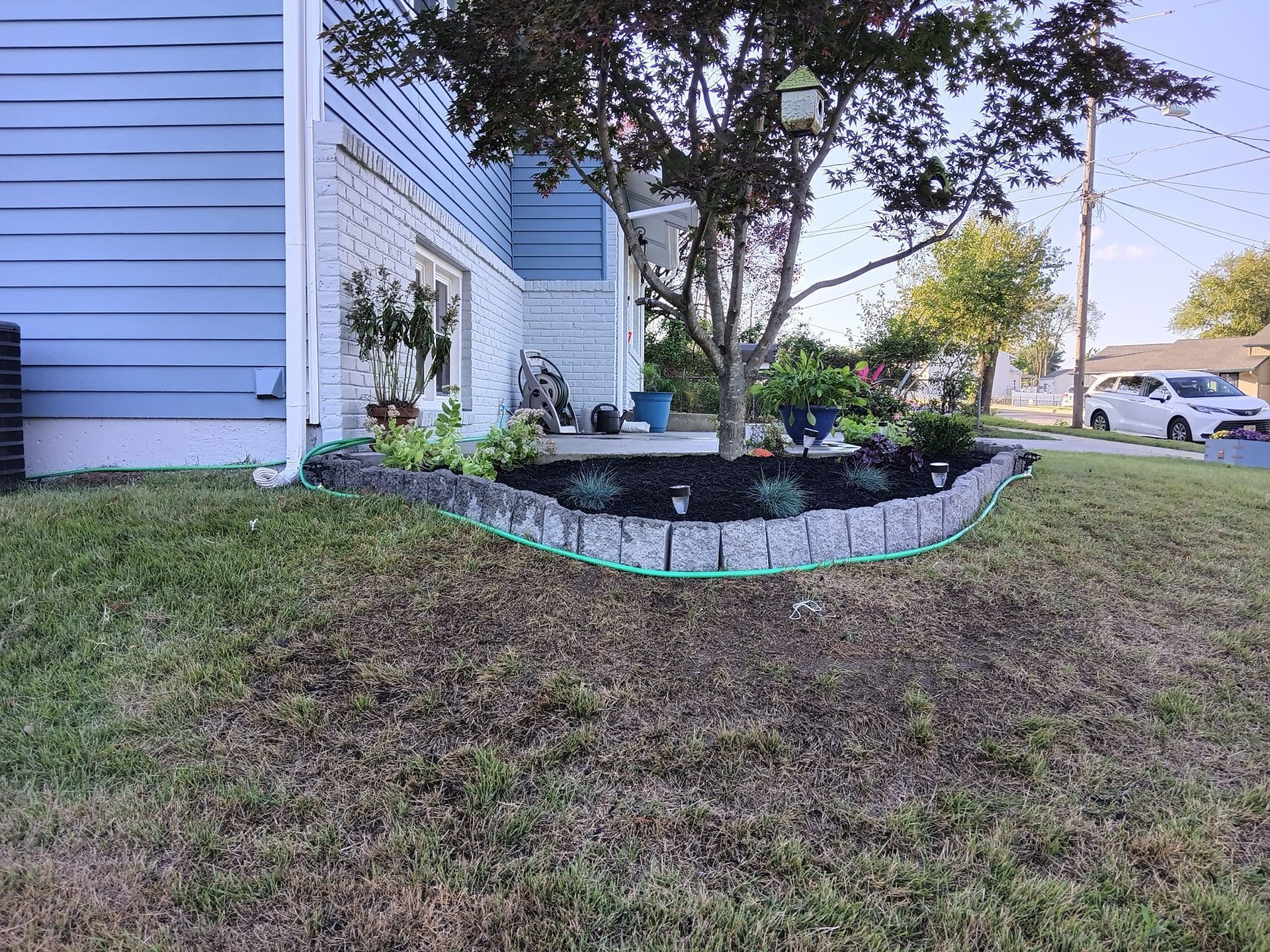 A blue house with a lush green lawn in front of it.