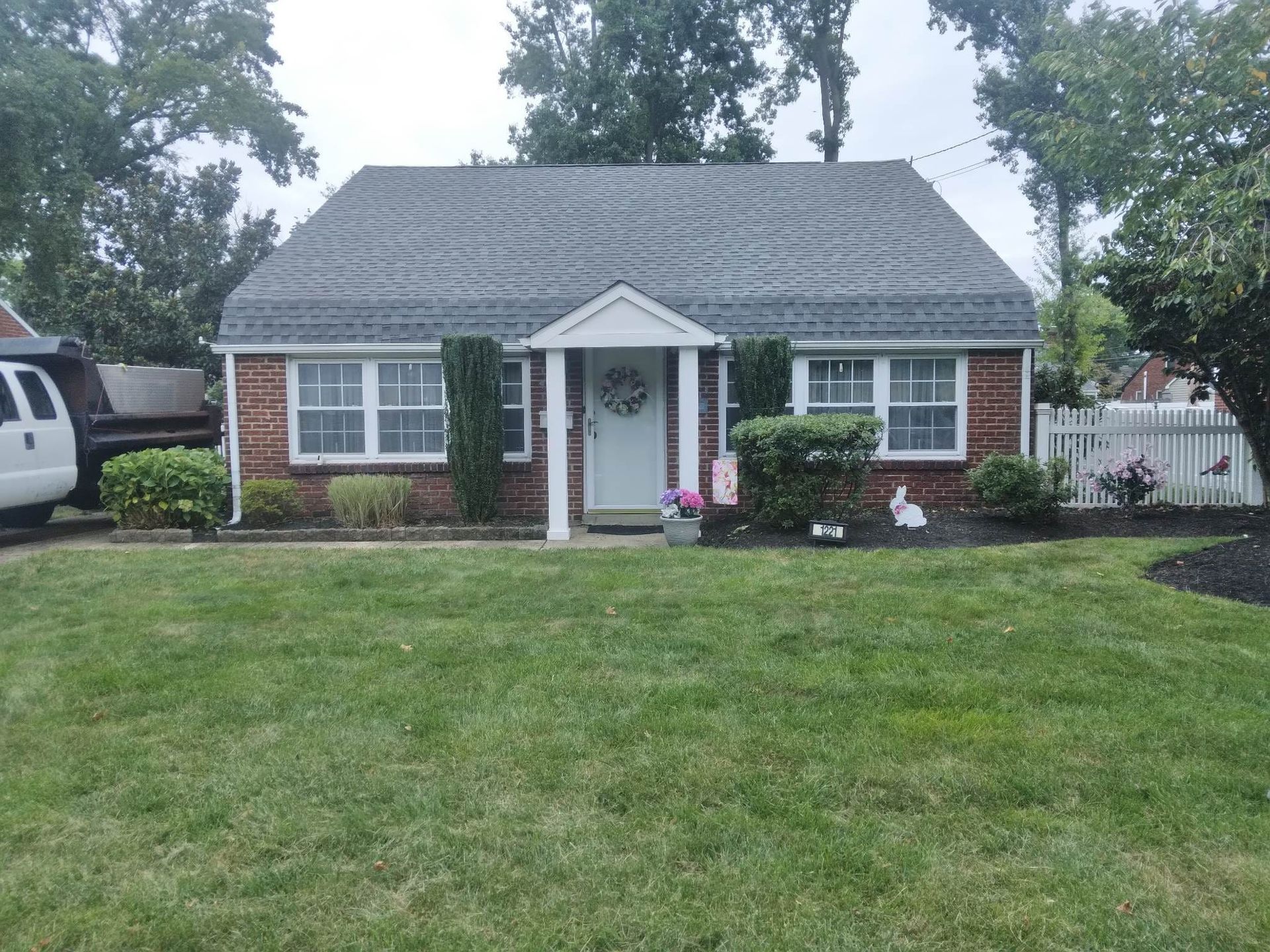 A brick house with a gray roof and a white van parked in front of it.