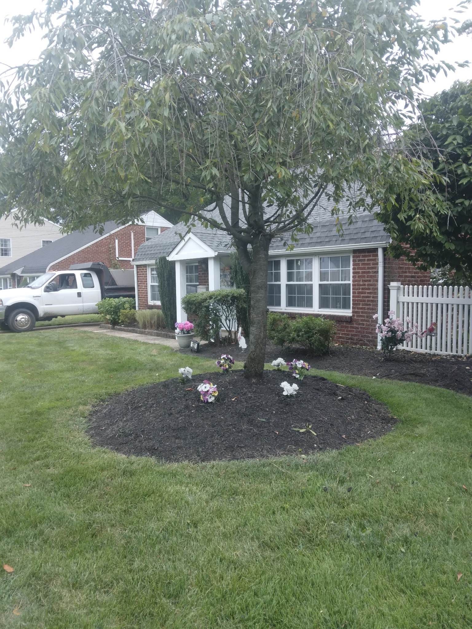 A white truck is parked in front of a brick house.