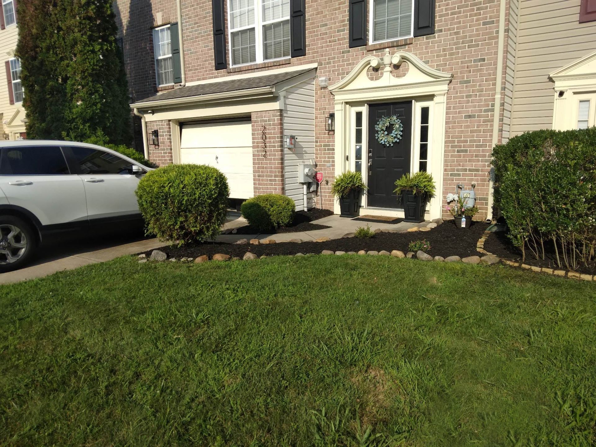 A white suv is parked in front of a brick house.