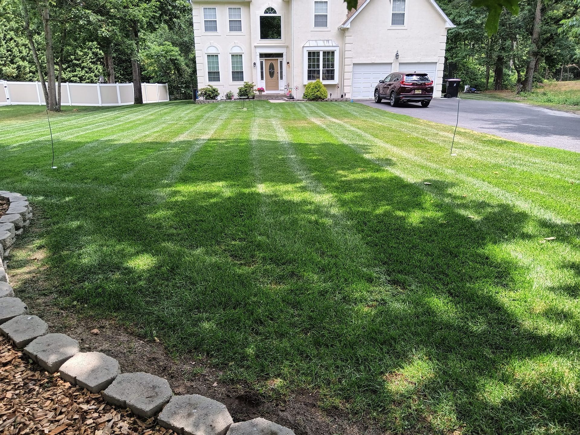 A white house with a lush green lawn and a car parked in front of it.