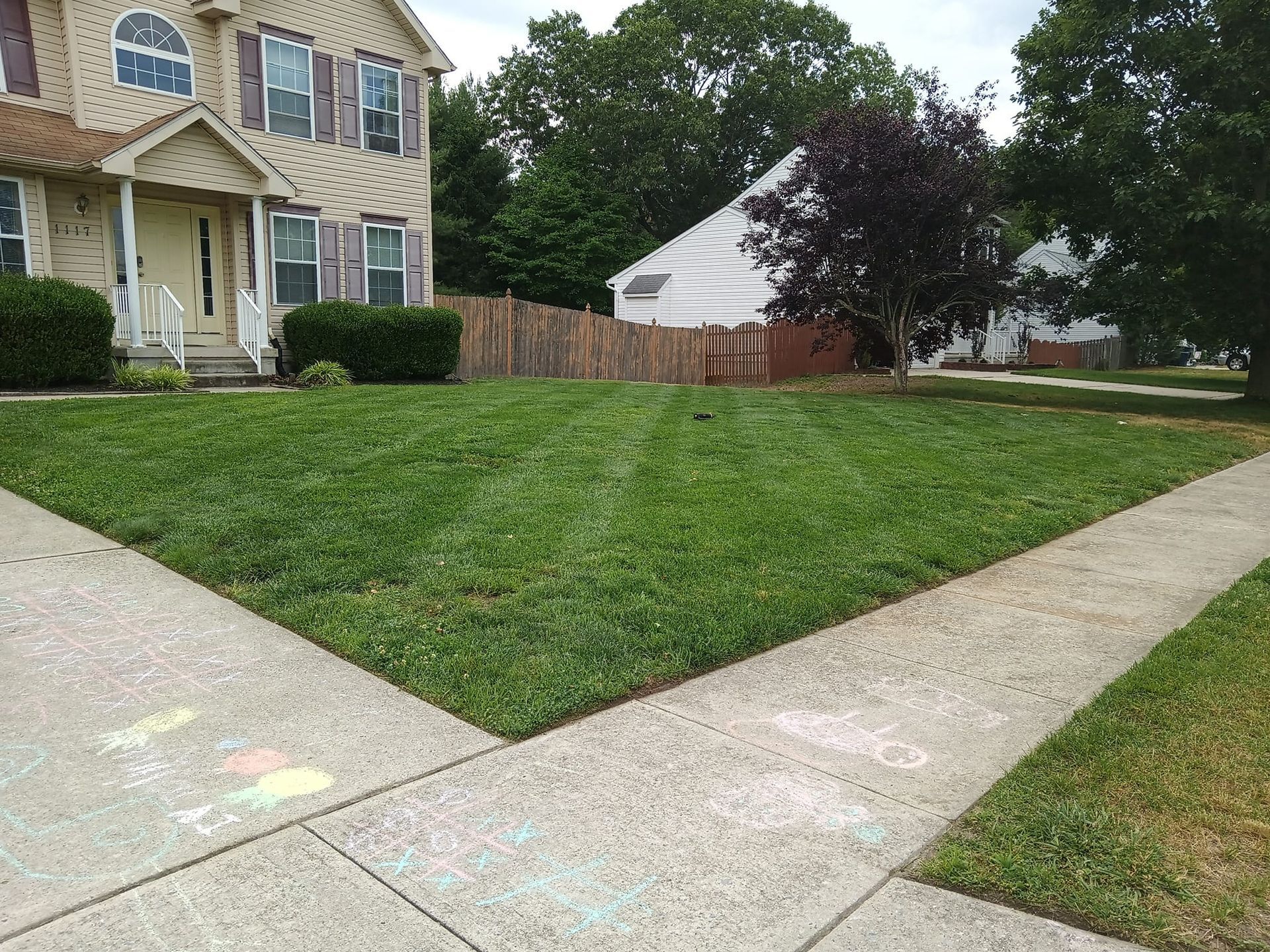 A house with a lush green lawn and a sidewalk in front of it.
