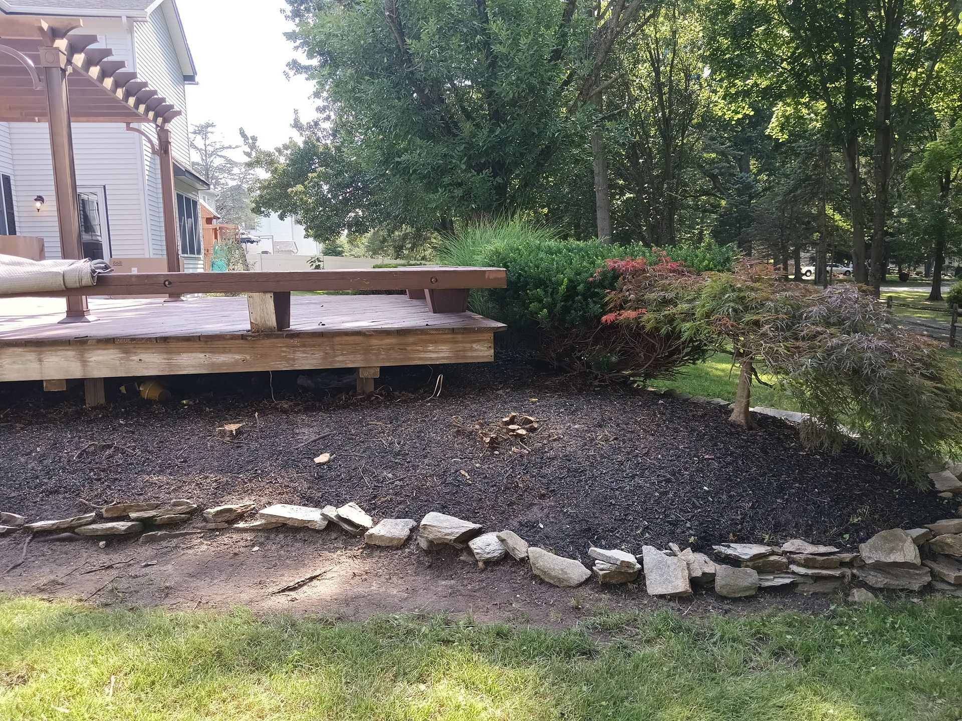 A wooden deck is sitting in the middle of a lush green yard.