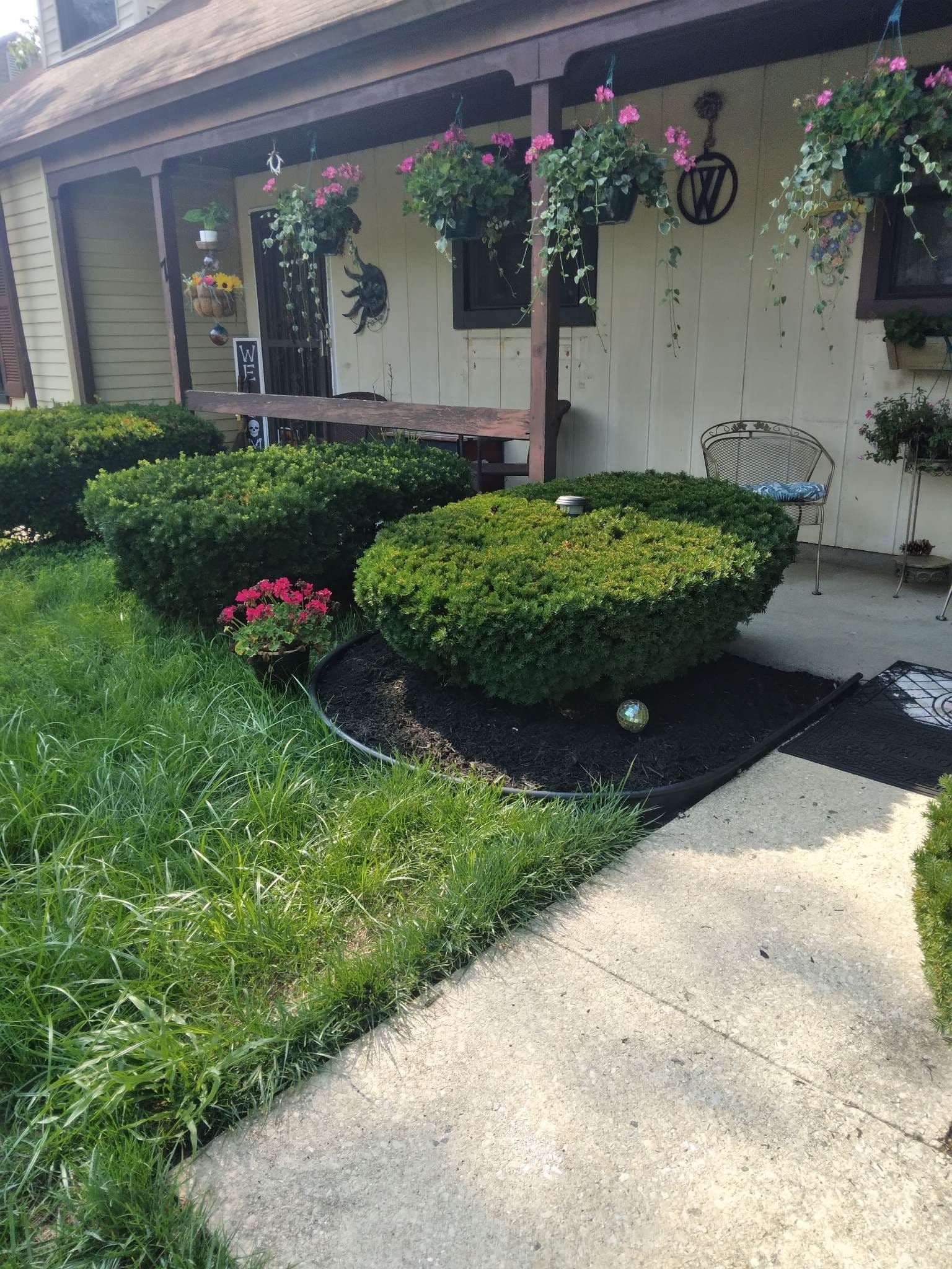A house with a porch and bushes in front of it.