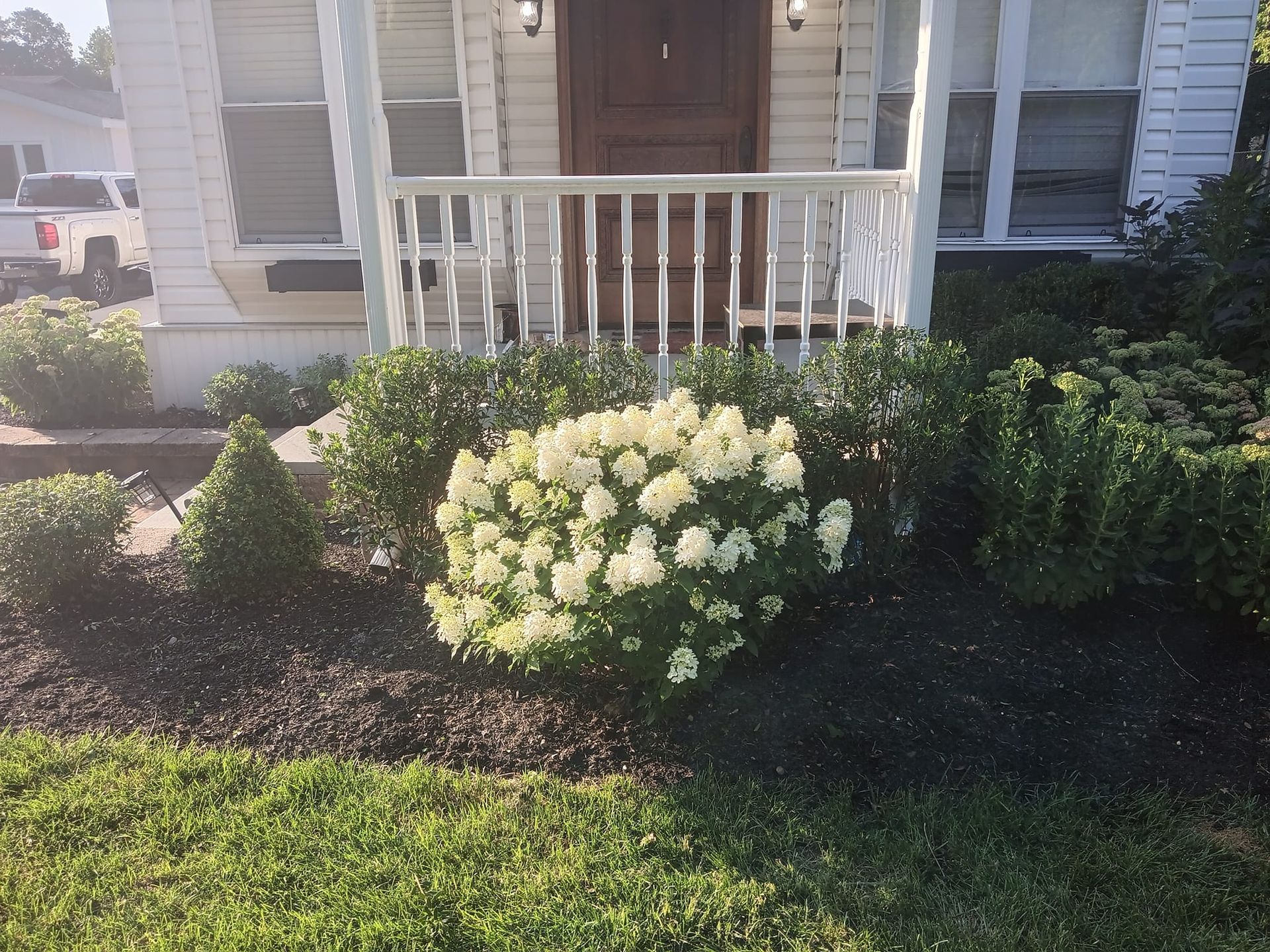 A white house with a porch and flowers in front of it