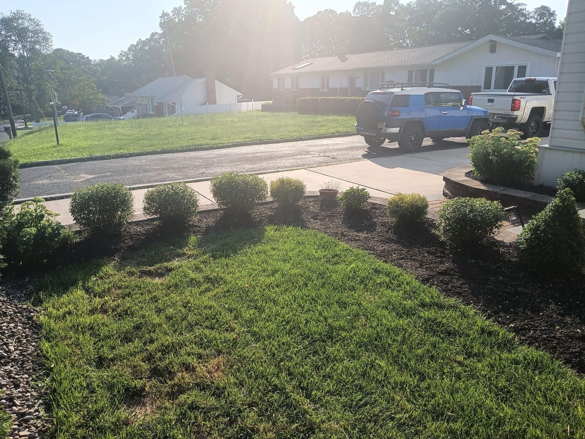A blue truck is parked in a driveway in front of a house.
