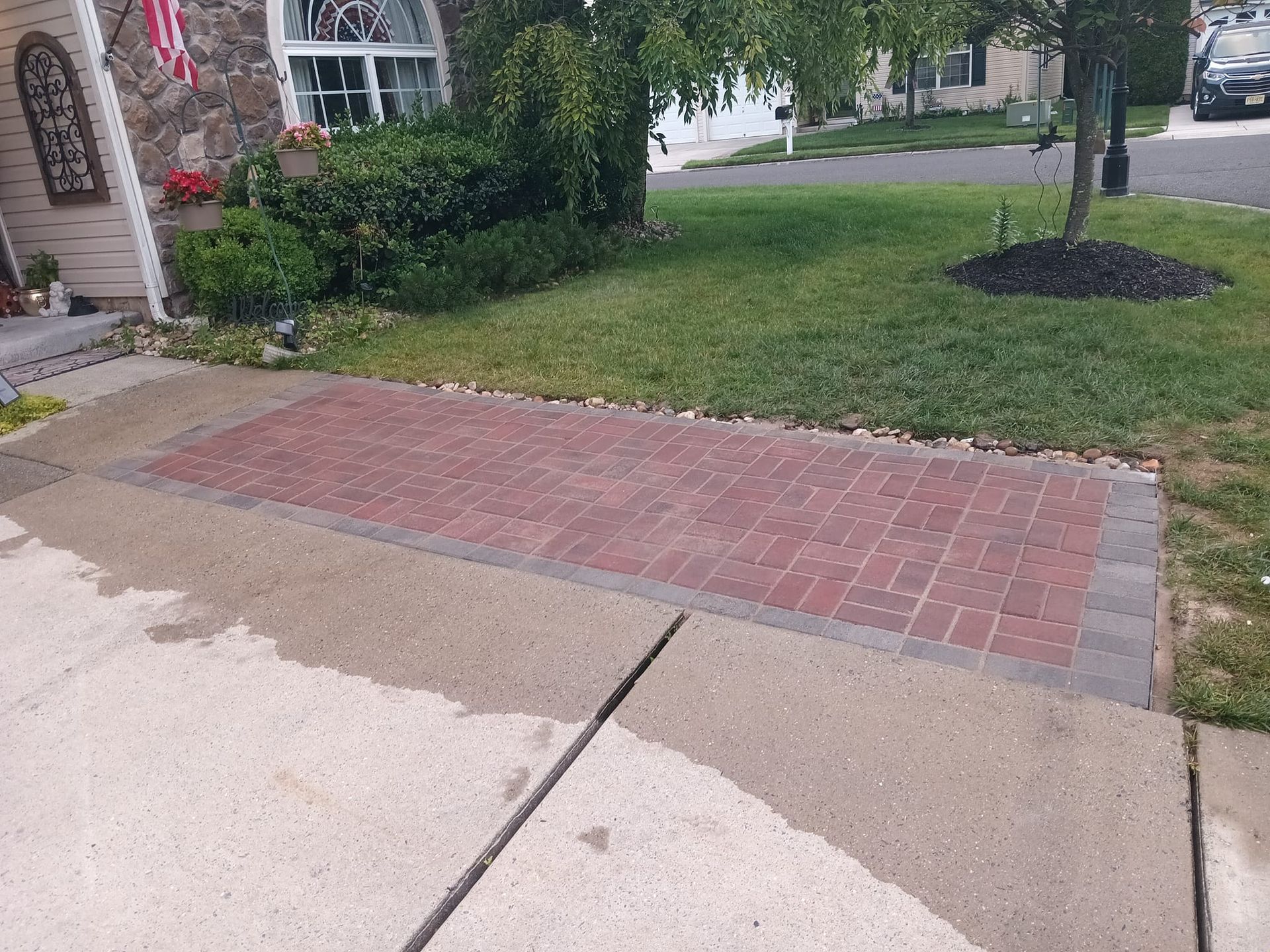 A driveway with a brick walkway leading to a house.
