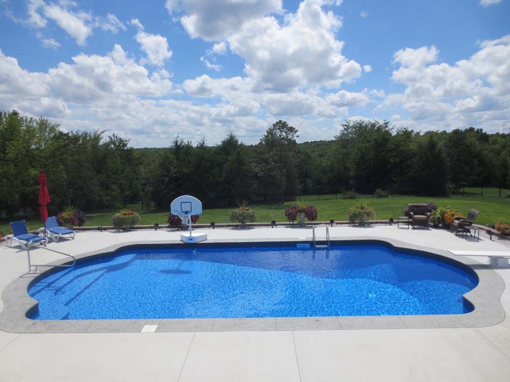 A large swimming pool with a basketball hoop in the backyard