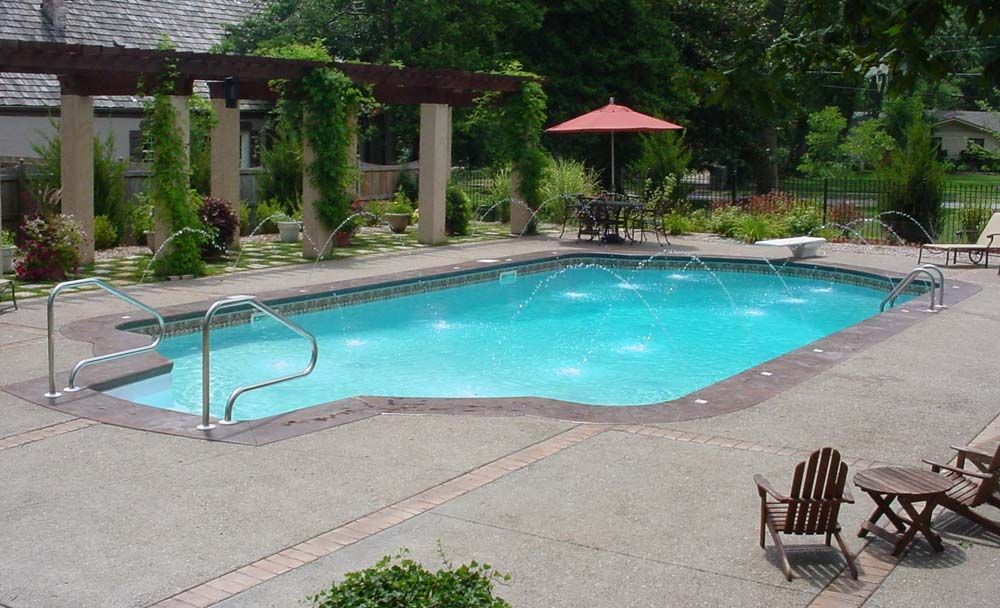 A large swimming pool with a red umbrella and chairs around it