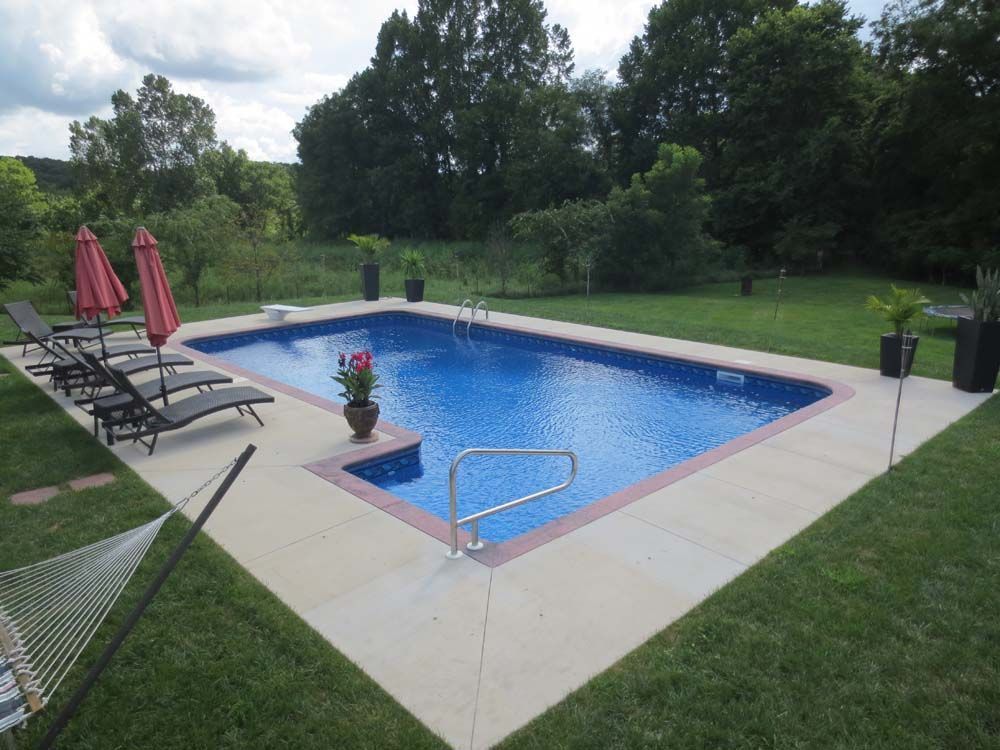 A large swimming pool surrounded by chairs and umbrellas